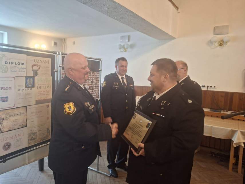 Przewodniczący Rady Miejskiej Czesław Greń oraz Naczelnik OSP Bąków Marcin Kajstura wręczają statuetkę św. Floriana i tabliczkę pamiątkową z życzeniami